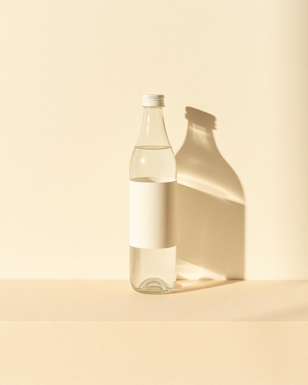 Minimal branded water bottle still life on a warm off-white surface